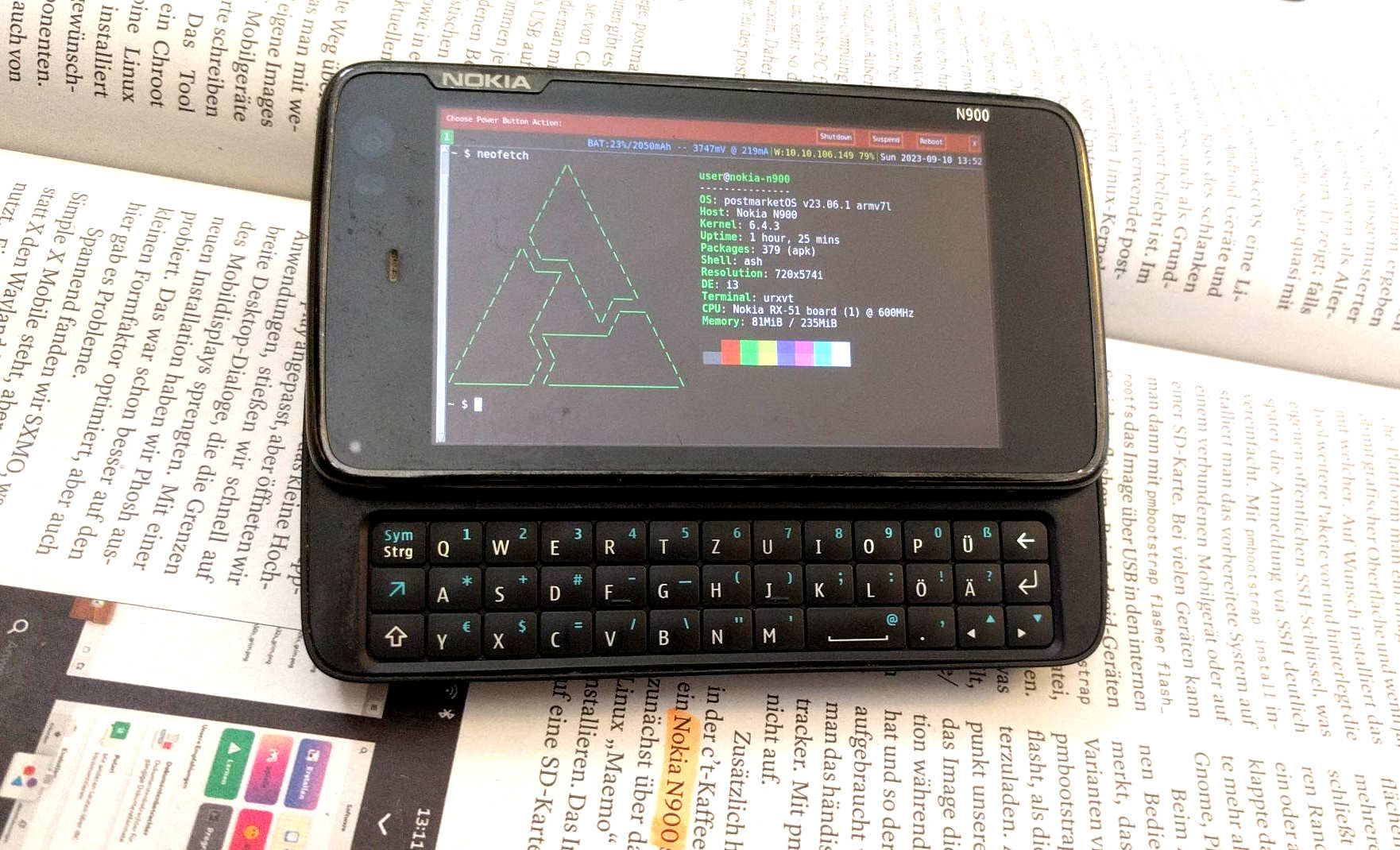 Nokia N900 with v23.06 SP1 installed, showing a terminal with neofetch, on top of the latest c't magazine with an article about postmarketOS in which the string "Nokia N900" was highlighted manually with a text marker